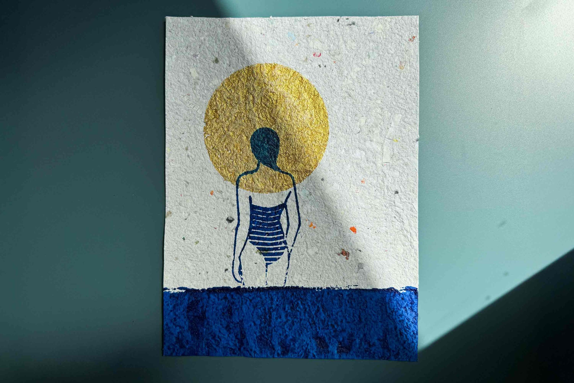 Siebdruckkunst Plakat Mare vor blauem Hintergrund: schimmerndene goldene Sonne, blaues Wasser und Silhouette die in die Ferne guckt. Handbedruckt auf selbst geschöptem Papier, Upcycling Altpapier