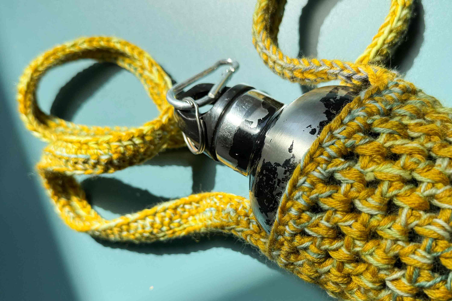 Detailansicht eines gelben gehäkelten Flaschenhalters zum Umhängen aus geretteter Wolle