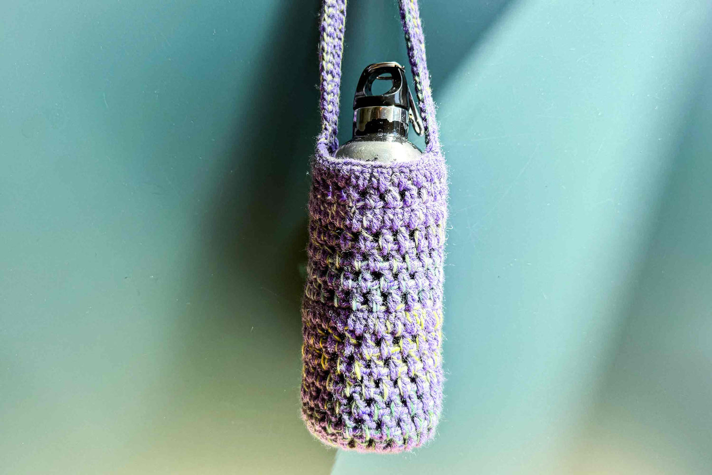 Hängender, gehäkelter Flaschenhalter in lila bunt gemixter Wolle