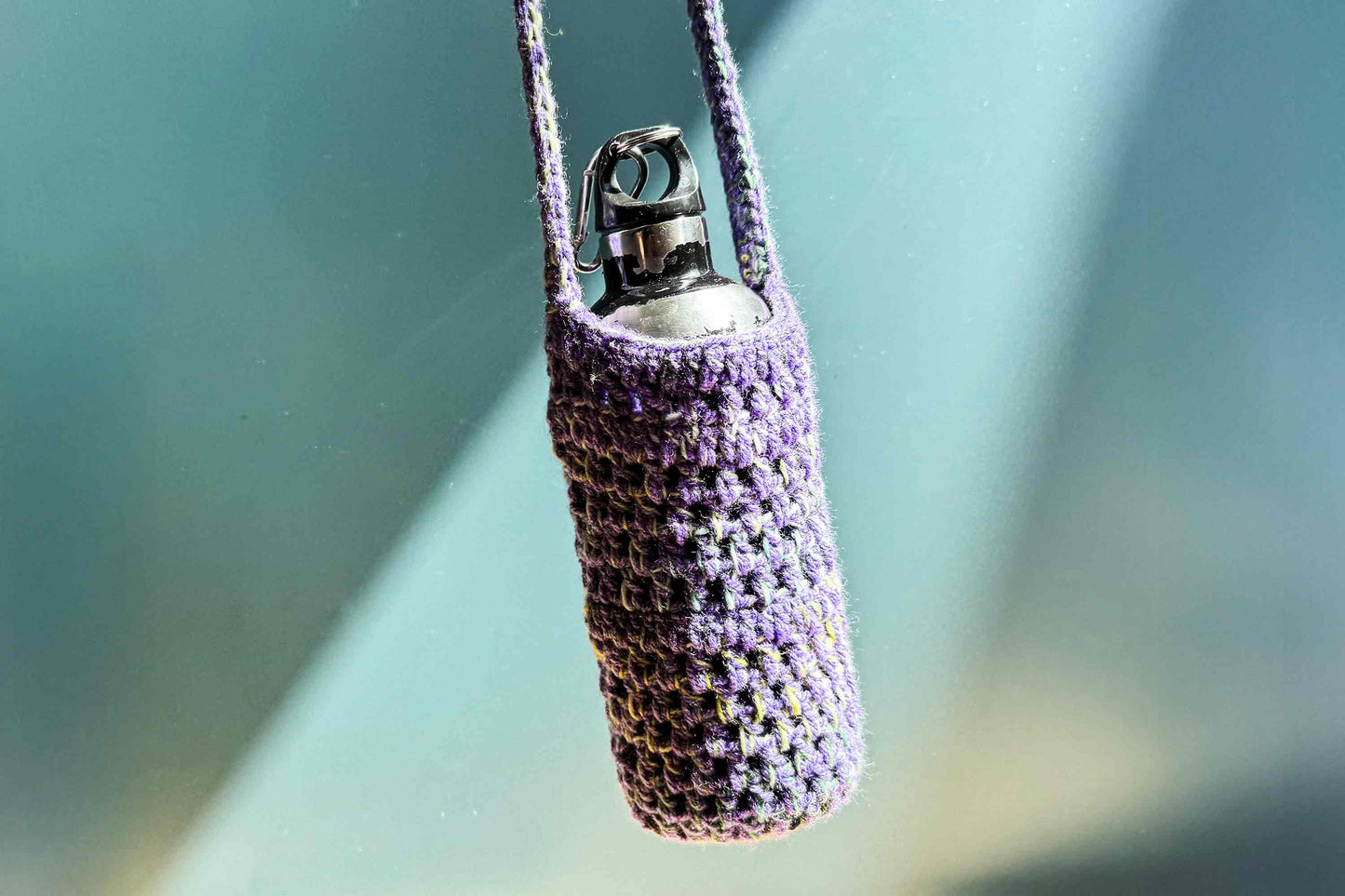Hängender, gehäkelter Flaschenhalter in lila bunt gemixter Wolle