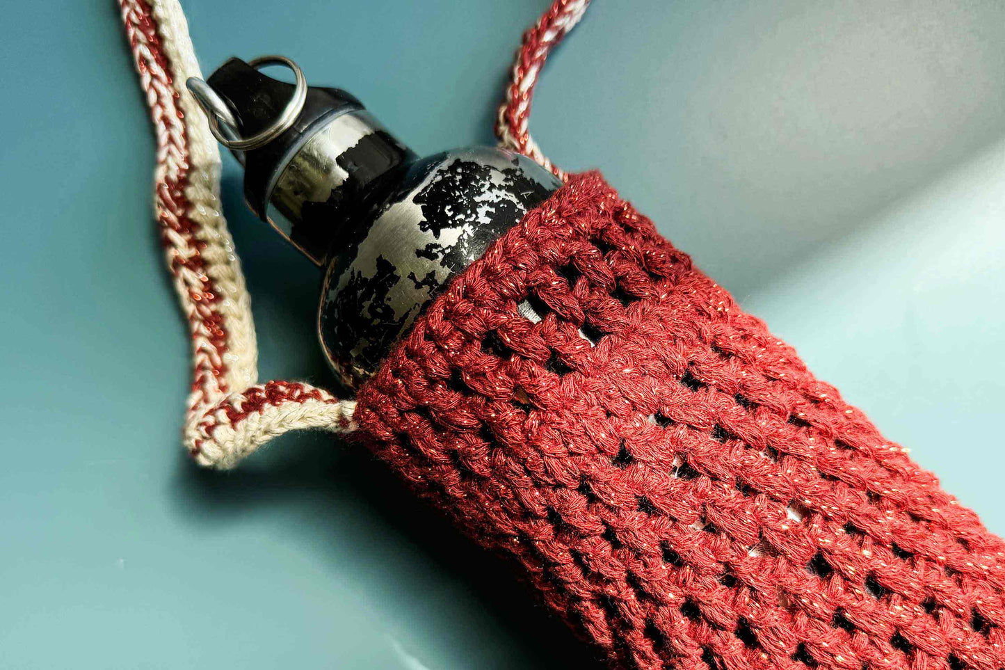 Detailansicht des gehäkelten, rot glitzernden Flaschenhalters zum Umhängen CHRISTA mit Trinkflasche