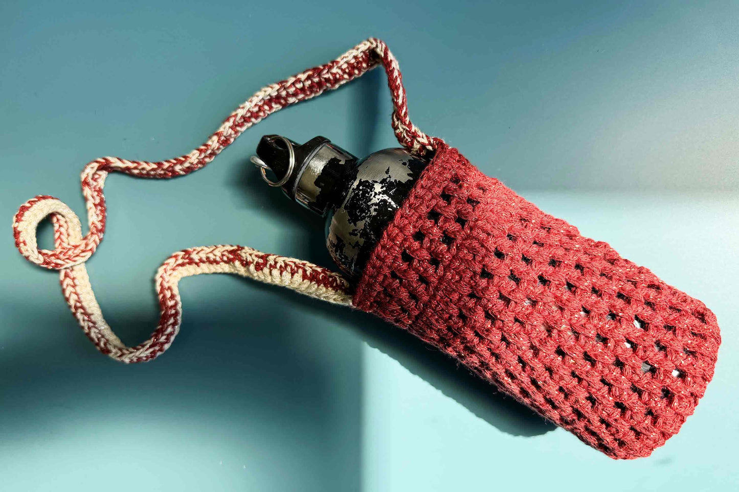 Gesamtansicht des gehäkelten, rot-beige glitzernden Flaschenhalters zum Umhängen CHRISTA mit Trinkflasche
