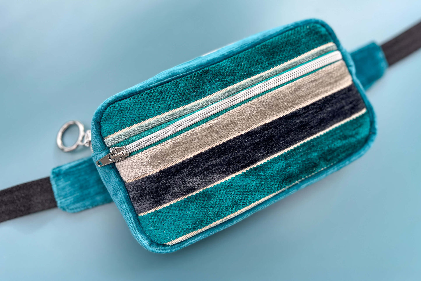 Gesamtansicht einer Bauchtasche aus Samt von Jeff EveryPieceAFriend. Die Tasche ist blau und grau gestreift, hat ein schwarzes Gurtband und einen silbernen Reißverschluss.
