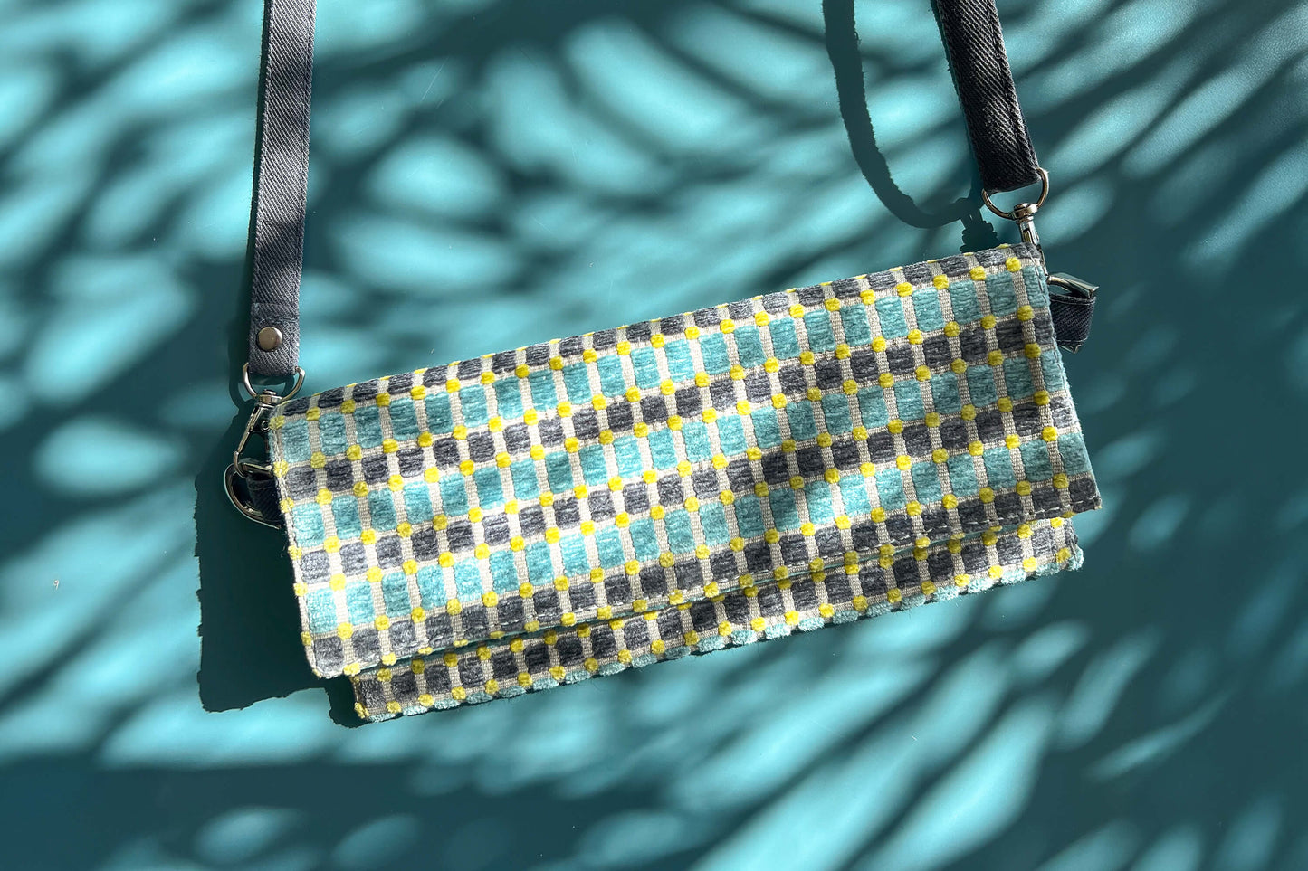 Gesamtansicht der kleinen Umhängetasche DANA aus upcycled Polsterstoff in den Farben blau, gelb und beige mit silbernen Verschlüssen.