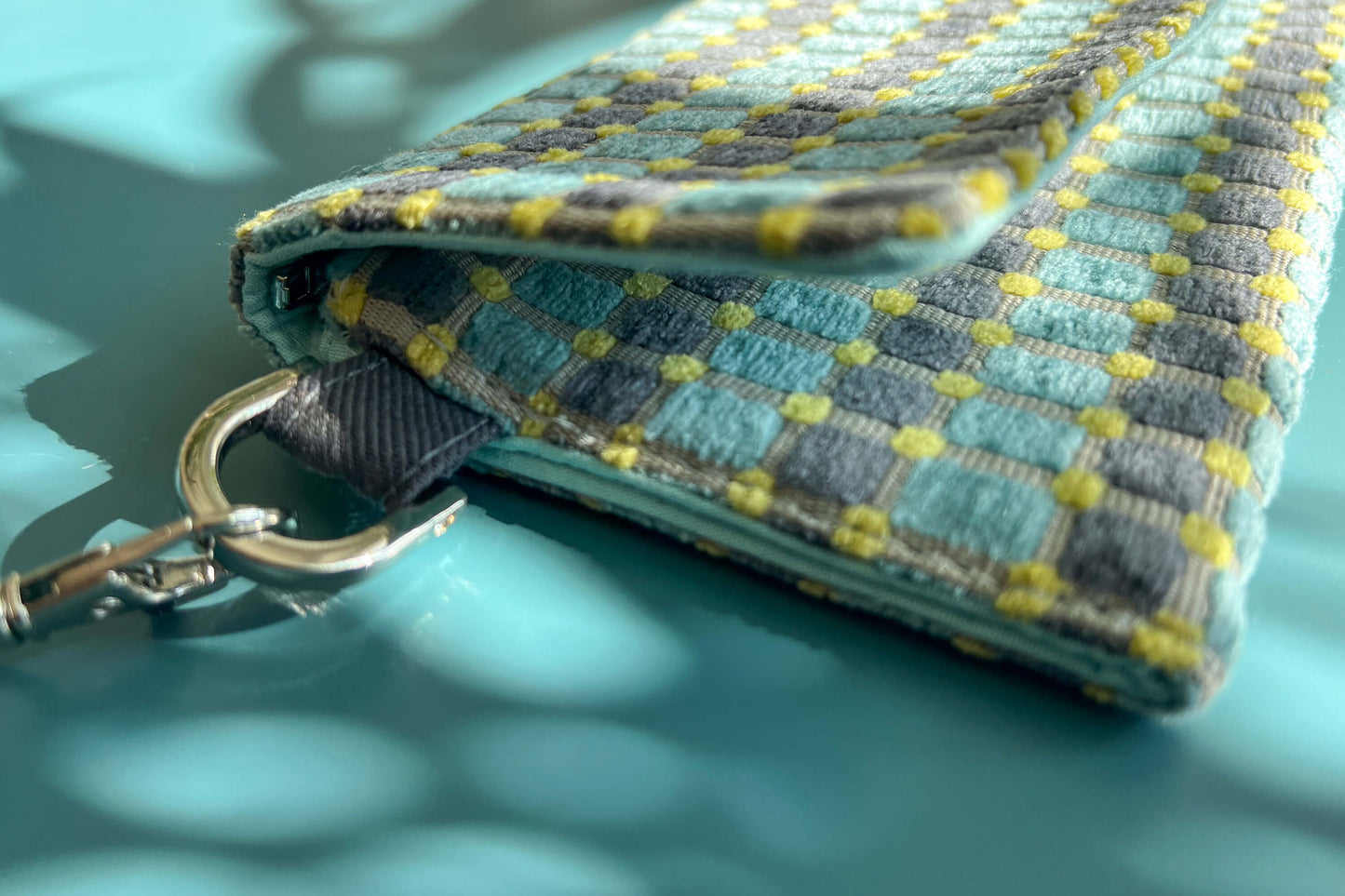 Detailansicht der kleinen Umhängetasche DANA aus upcycled Polsterstoff in den Farben blau, gelb und beige mit silbernen Verschlüssen.