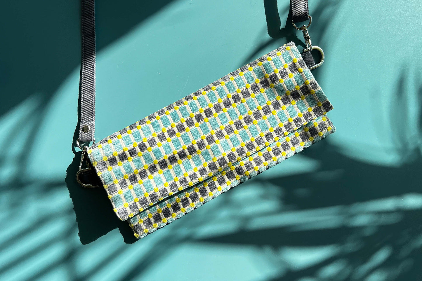 Gesamtansicht der kleinen Umhängetasche DANA aus upcycled Polsterstoff in den Farben blau, gelb und beige mit silbernen Verschlüssen.