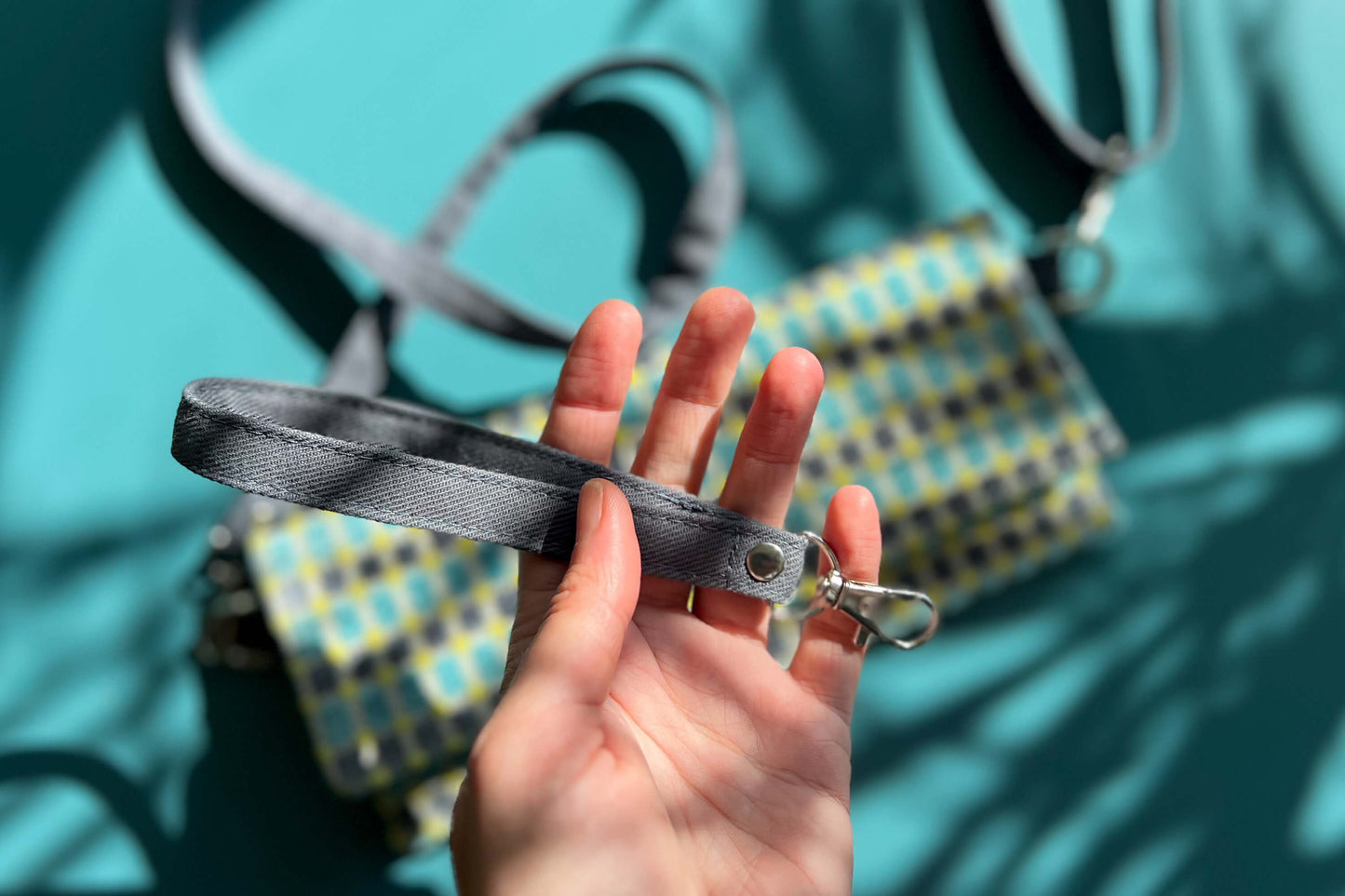 Detailansicht: Hand hält abnehmbares Gurtband der kleinen Tasche DANA in die Kamera.