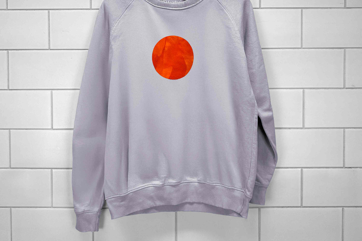 Frontansicht von lilafarbenen Sweatshirt mit einem bedruckten Kreis in orange. Siebdruck von Jeff EveryPieceAFriend.