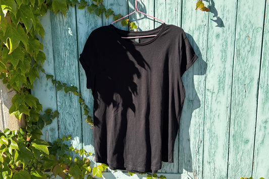 Gesamtansicht von einem schwarzen T-Shirt vor einem blauen Hintergrund.