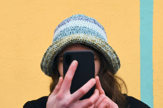 Frau schaut aufs Handy und trägt gehäkelten Anglerhut FIETE