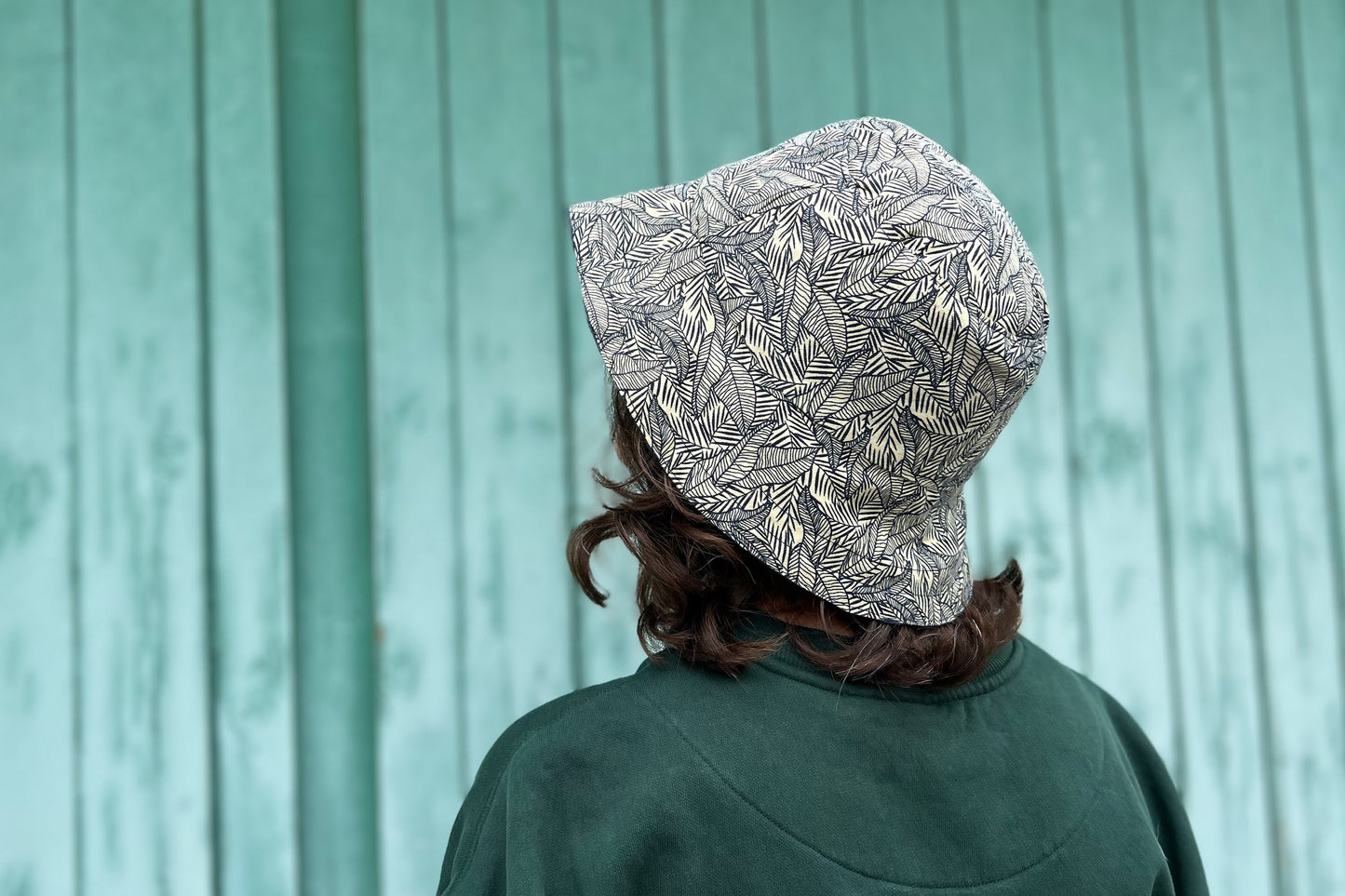 Frau trägt wendbaren weißen Sommerhut mit blauem Blattmuster LUCA aus Upycling-materialien