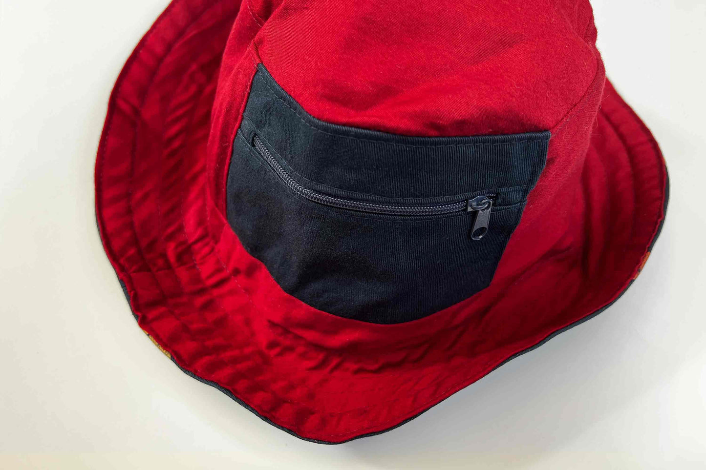 Roter wendbarer Anglerhut aus Upcycling-Materialien mit kleinem Reisverschlussfach