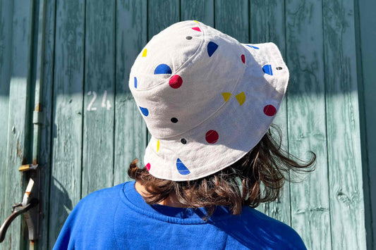 Frau trägt wendbaren Anglerhut aus Upycling-materialien von Hand bedruckt bunten geometrischen Formen