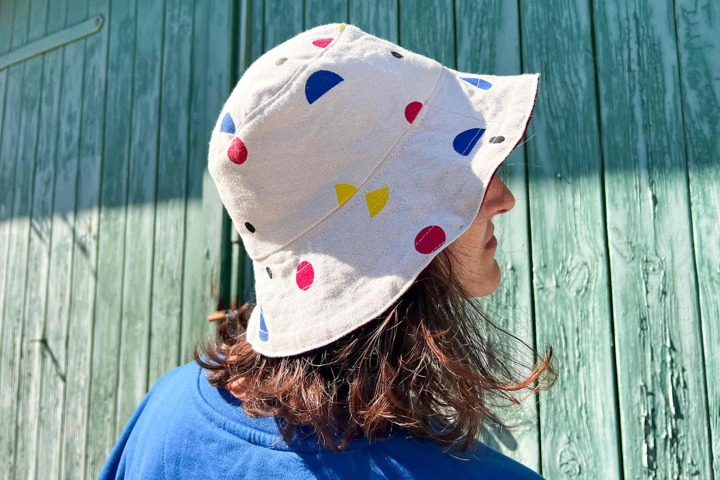 Frau trägt wendbaren Buckethat aus Upycling-materialien von Hand bedruckt bunten geometrischen Formen