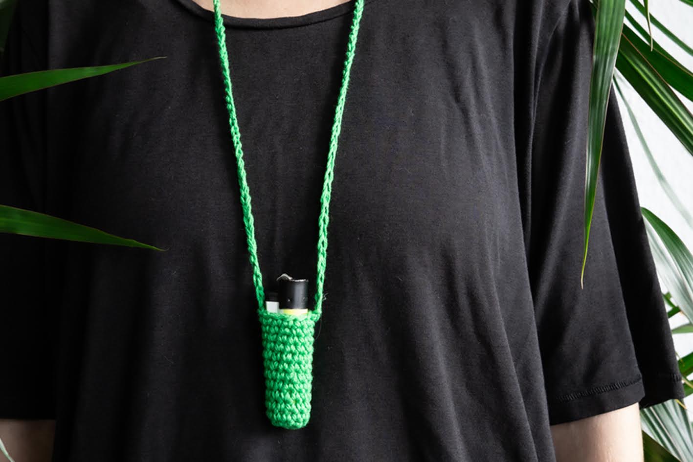 Grüner gehäkelter Feuerzeug- oder Lippenstifthalter umgehängt als Halskette