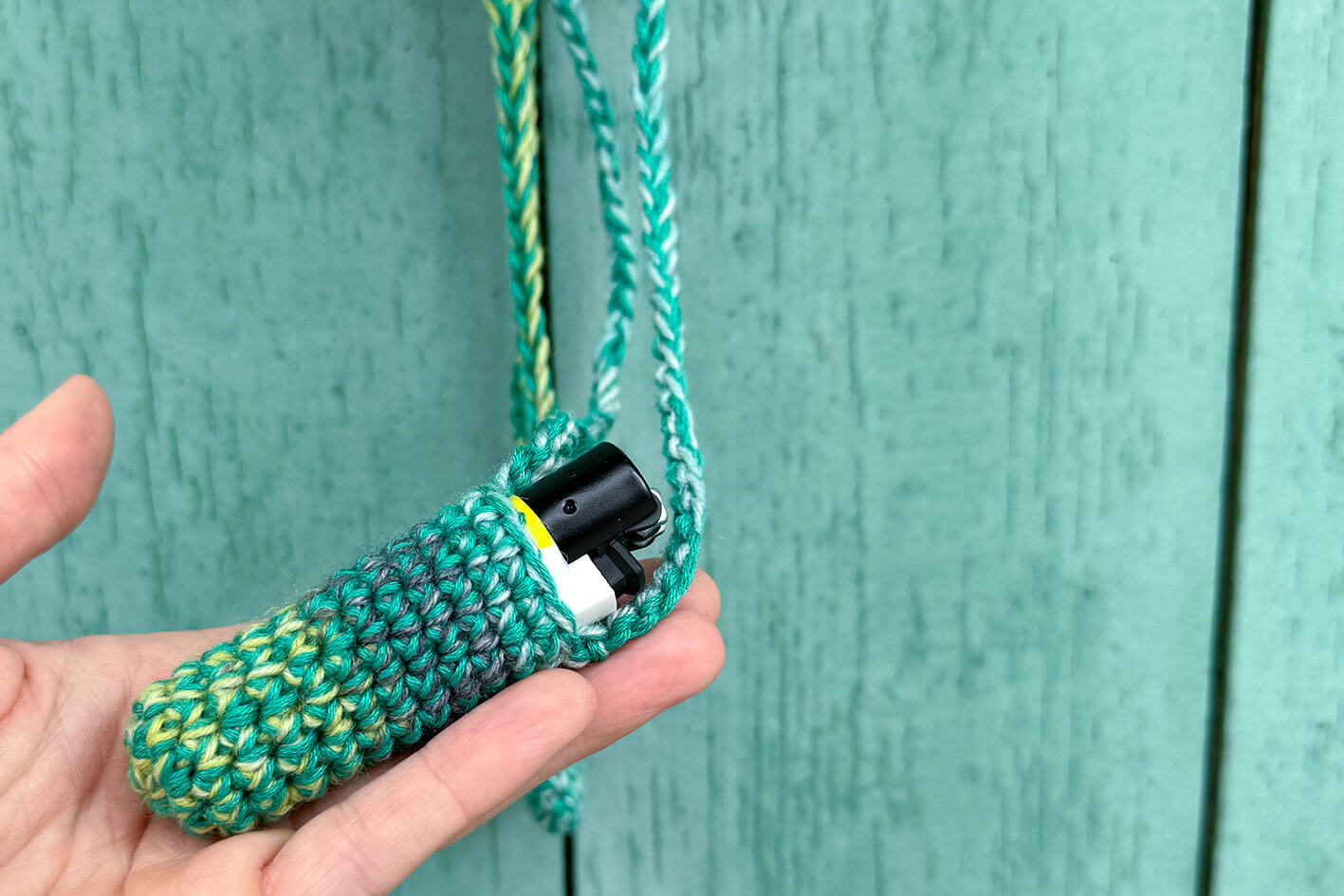 Zwei gehäkelte Taschen fürs Feuerzeug in verschiedenen Grüntönen.