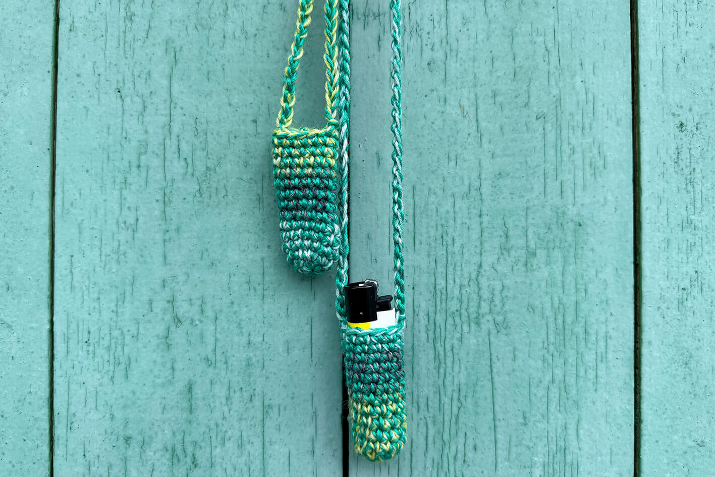 Zwei gehäkelte Taschen fürs Feuerzeug in verschiedenen Grüntönen.