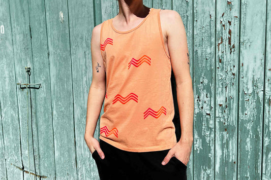 Mann trägt pfirsichfarbenes Unisex Tanktop mit wellenförmigem Siebdruck in orange rot Verlauf