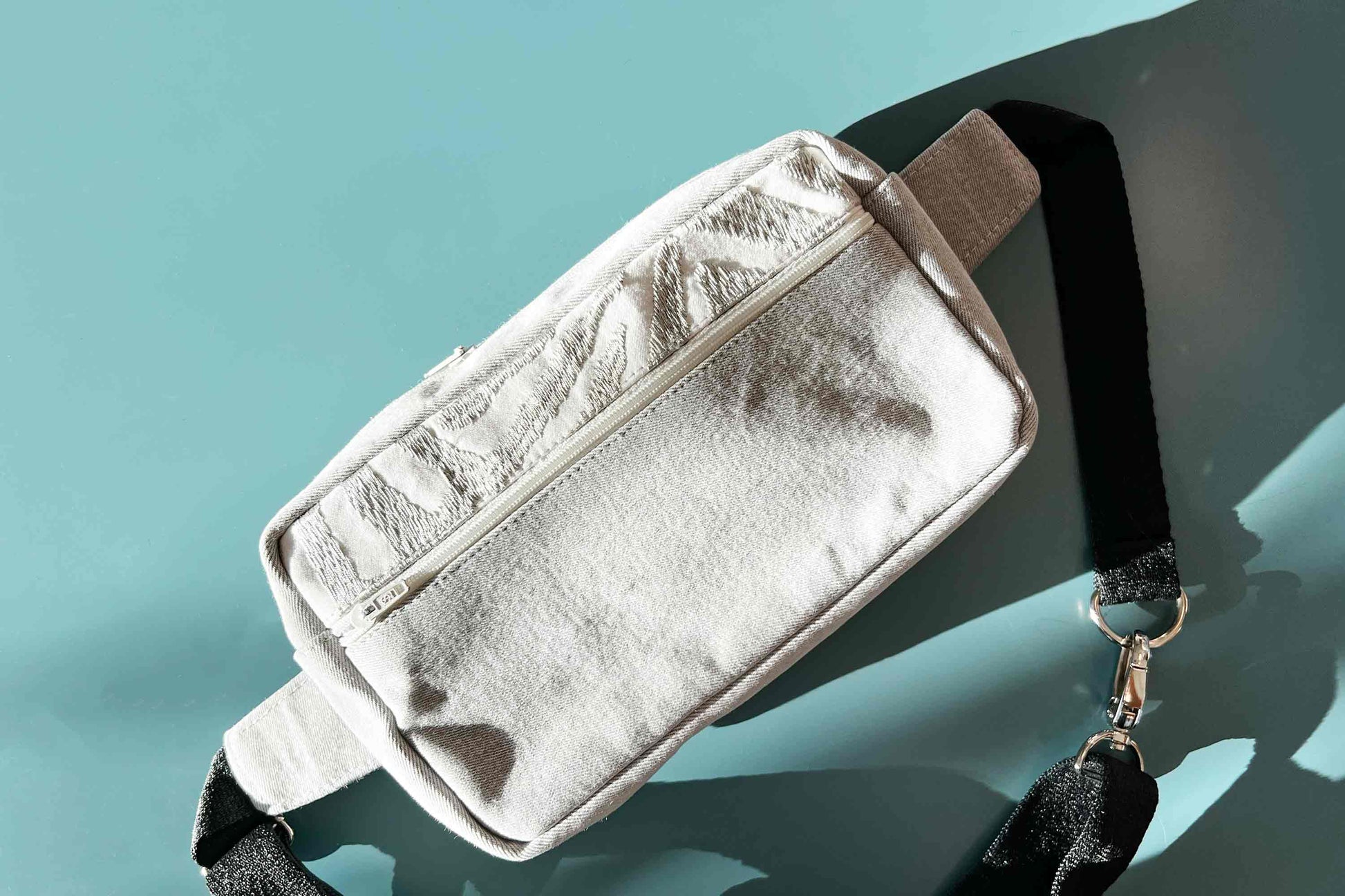 Coole Umhängetasche Hipbag upcycling aus grauer Jeans von jeff every piece a friend auf blauem Tisch