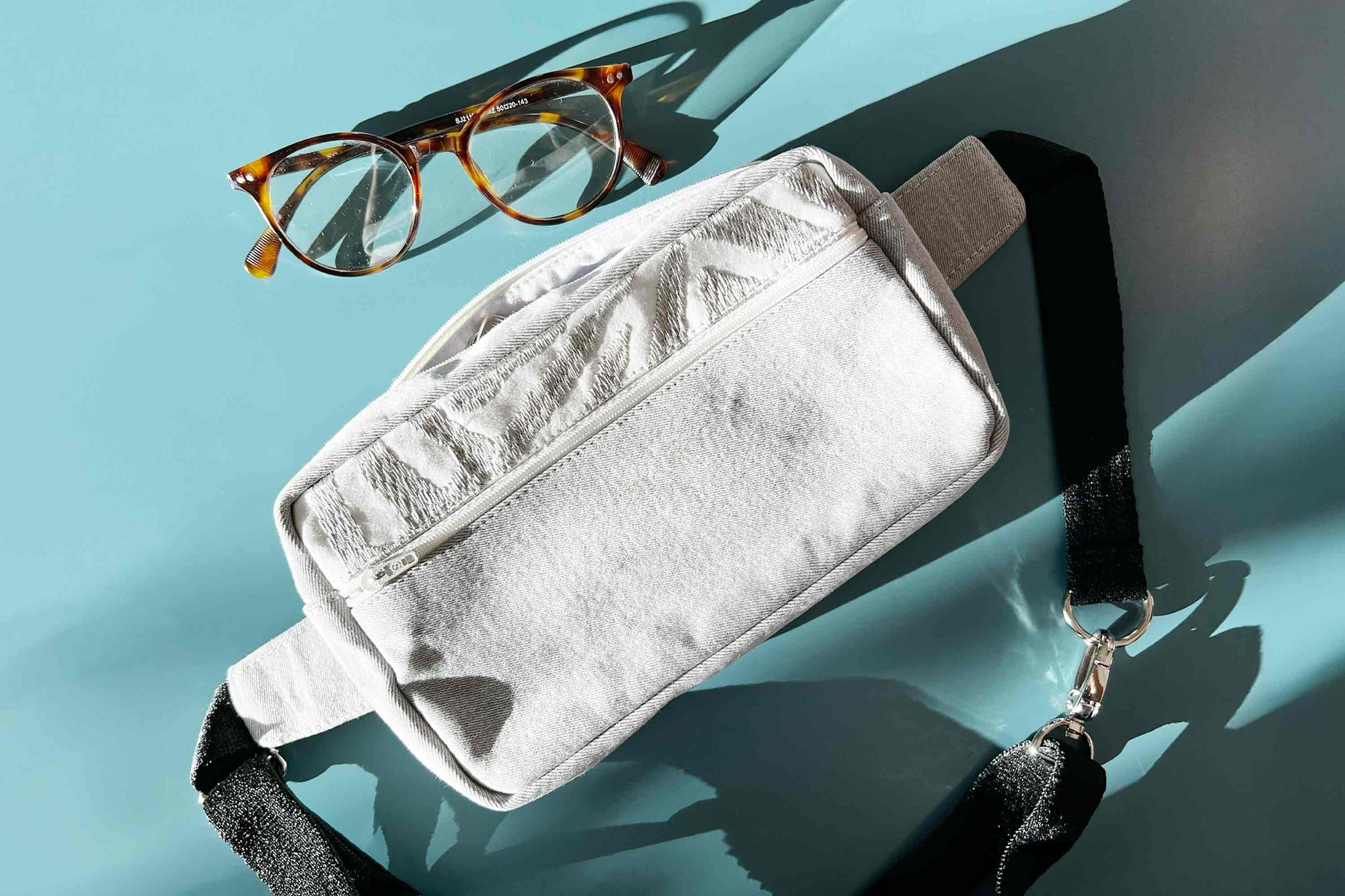 Coole Umhängetasche Hipbag upcycling aus grauer Jeans von jeff every piece a friend auf blauem Tisch