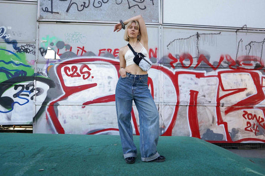 Junge Frau steht vor Graffiti-Wand und trägt Hipbag PAOLINA aus upgecyelten Materialien von jeff every piece a friend