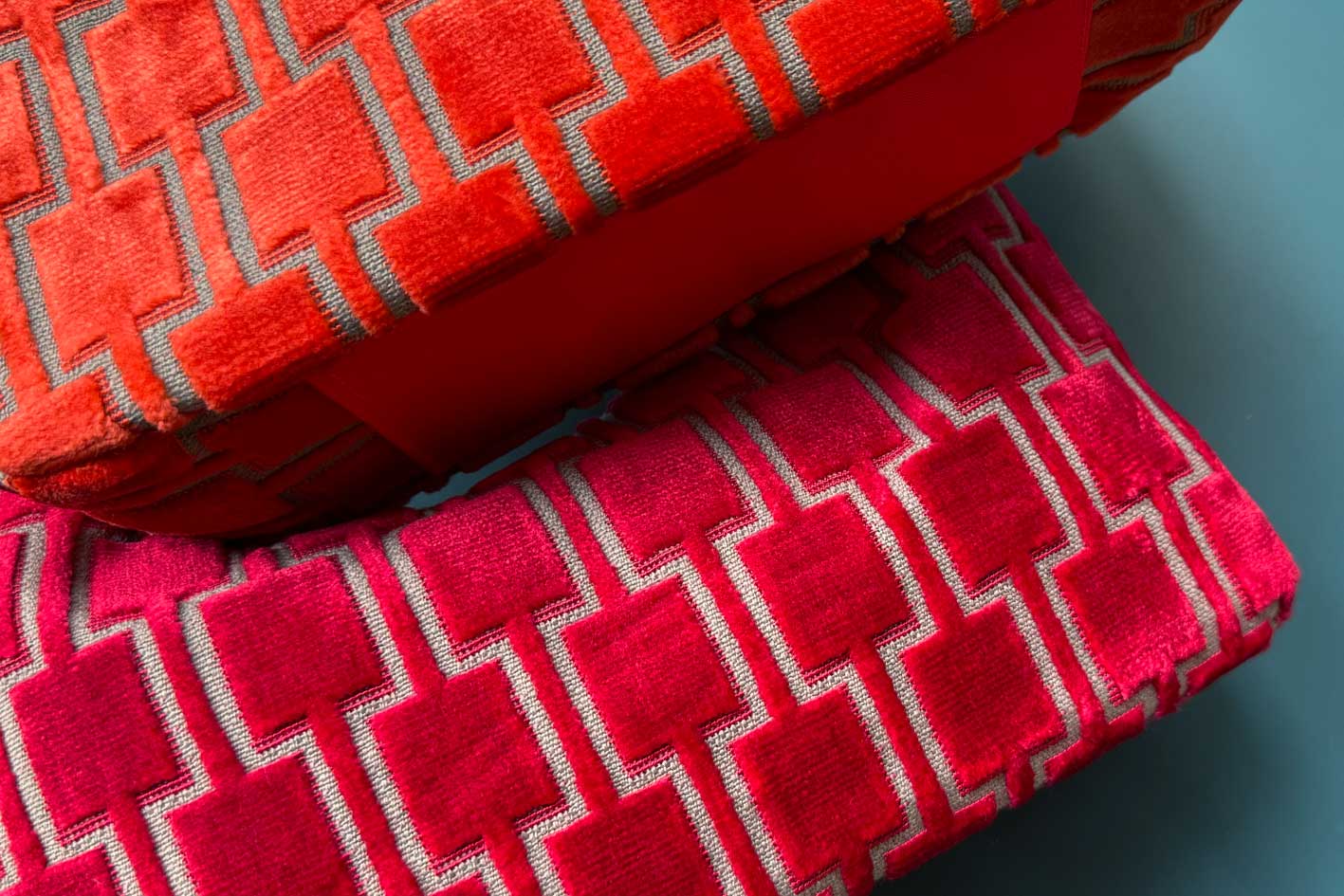 Detailansicht: Zwei Schultertaschen im Vintagestil vor blauen Hintergrund. Die obereTasche ist orange gemustert, die untere Tasche ist rot gemustert. Beide Taschen wurden von aus upcycled Materialien von Jeff Every Piece A Friend hergestellt.