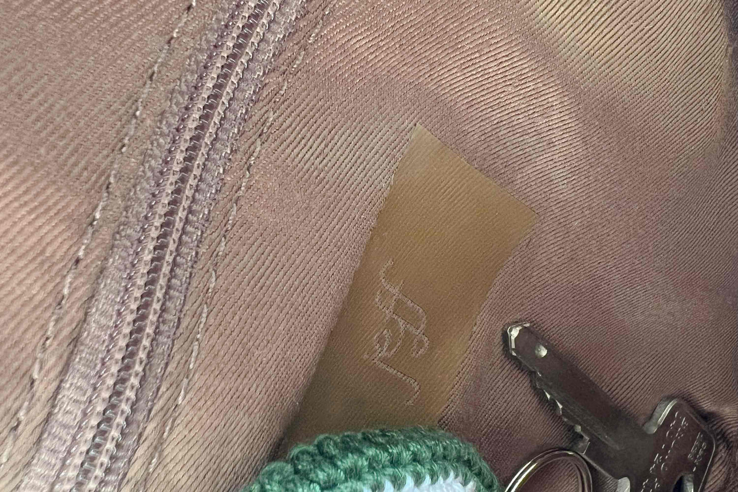 Detailansicht Innenfach der rundenUmhängetasche Peppa. Die Tasche besteht aus upcycled Materialien mit einem gehäkeltem Deckel in der Farbe gold.