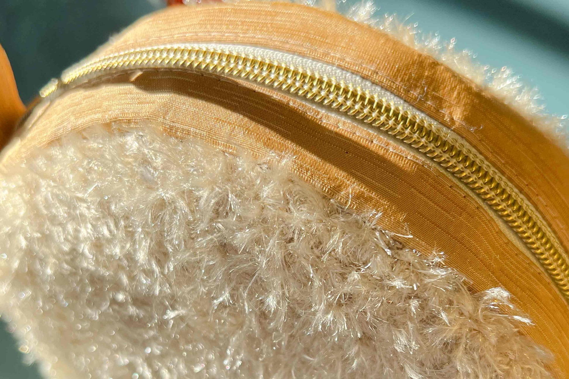 Detailansicht Reißverschluss. Runde Umhängetasche Peppa vor blauem Hintergrund. Tasche besteht aus upcycled Materialien.