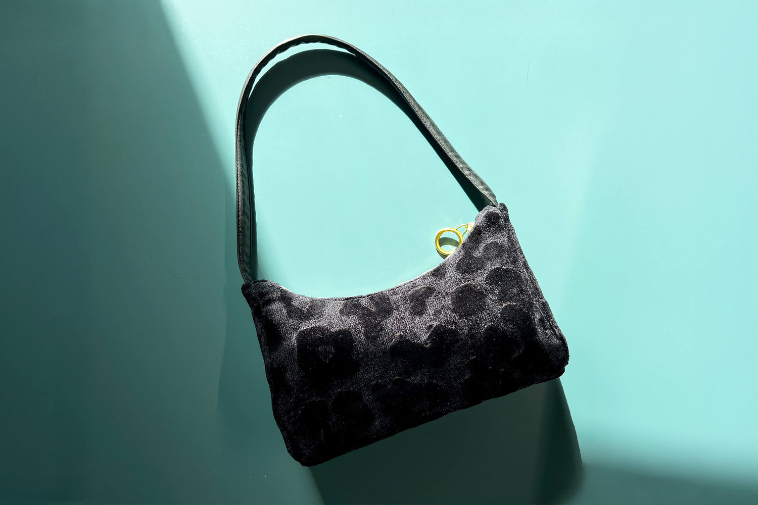 Runde Umhängetasche Peppa vor blauem Hintergrund. Tasche besteht aus upcycled Materialien mit gehäkeltem Deckel in der Farbe gold.