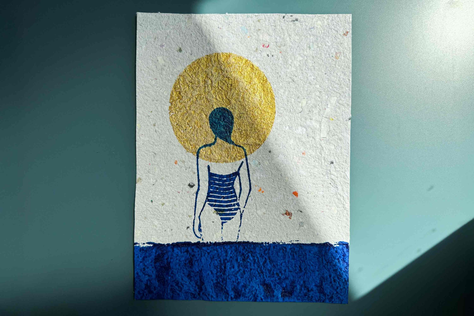 Siebdruckkunst Plakat Mare vor blauem Hintergrund: schimmerndene goldene Sonne, blaues Wasser und Silhouette die in die Ferne guckt. Handbedruckt auf selbst geschöptem Papier, Upcycling Altpapier