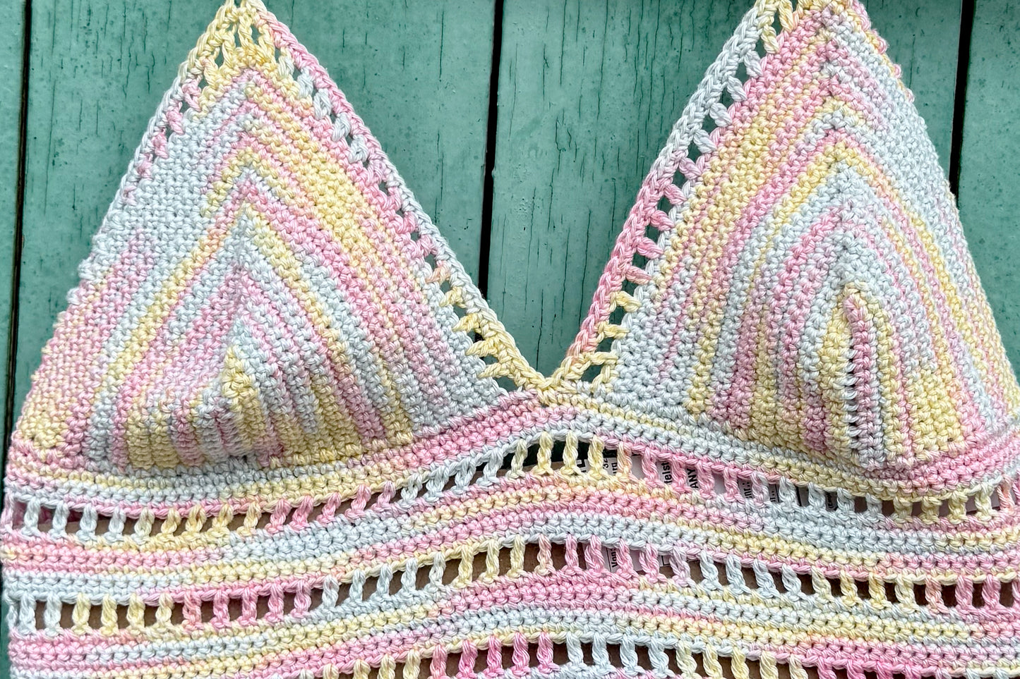Detailansicht Bustier: Gehäkeltes Sommertop Angie in pastelligen Farben vor blauem Hintergrund. 