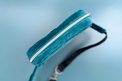 Gesamtansicht von oben einer Bauchtasche aus Samt von Jeff EveryPieceAFriend. Die Tasche ist blau und grau gestreift, hat ein schwarzes Gurtband und einen silbernen Reißverschluss. 