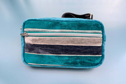 Gesamtansicht einer Bauchtasche aus Samt von Jeff EveryPieceAFriend. Die Tasche ist blau und grau gestreift, hat ein schwarzes Gurtband und einen silbernen Reißverschluss. 