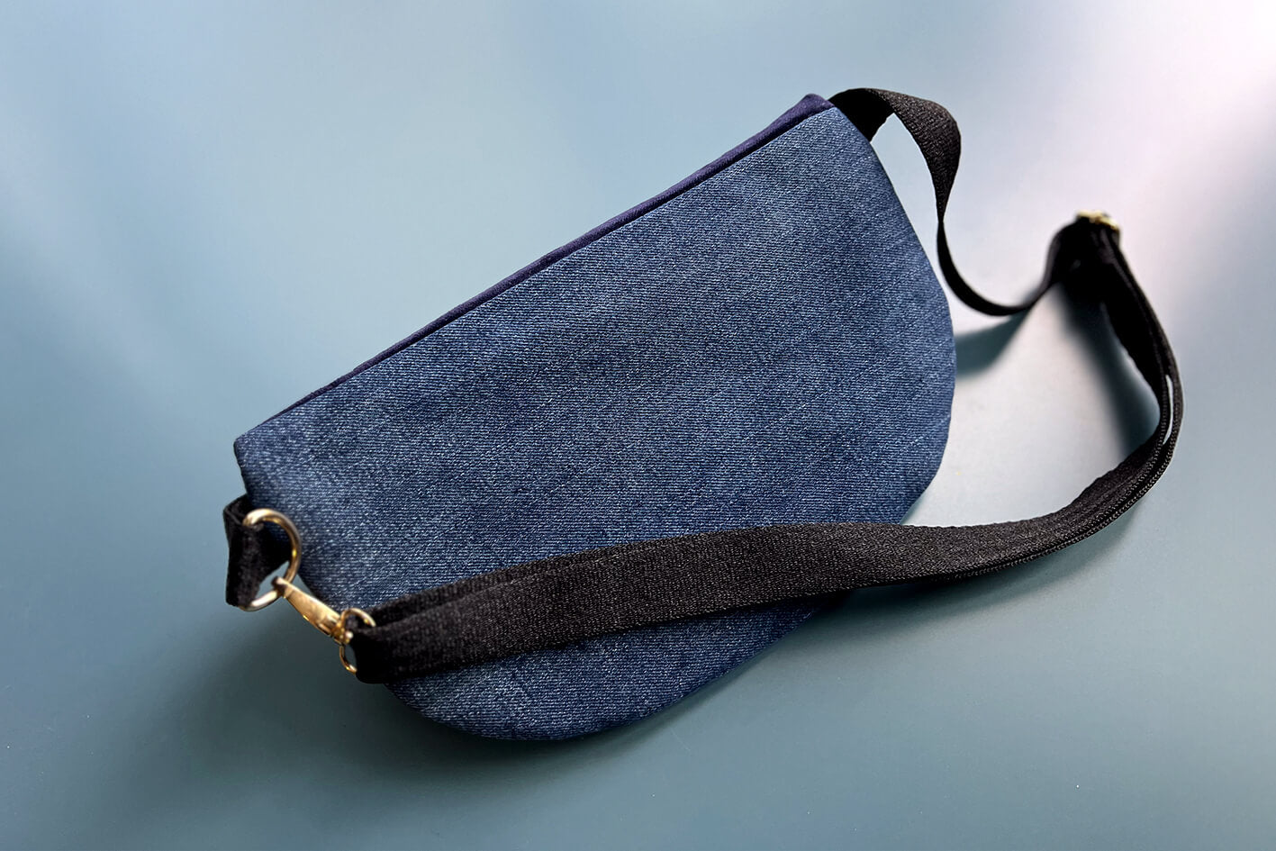 Gesamtansicht Rückenansicht einer großen Bauchtasche aus upcycled Denim. Die Tasche hat ein schwarzes Gurtband.