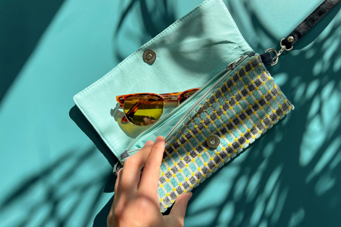 Gesamtansicht der kleinen, geöffneten Umhängetasche DANA aus upcycled Polsterstoff in den Farben blau, gelb und beige mit silbernen Verschlüssen. 