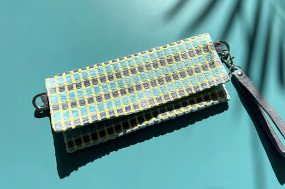 Gesamtansicht der kleinen Umhängetasche DANA aus upcycled Polsterstoff in den Farben blau, gelb und beige mit silbernen Verschlüssen. 