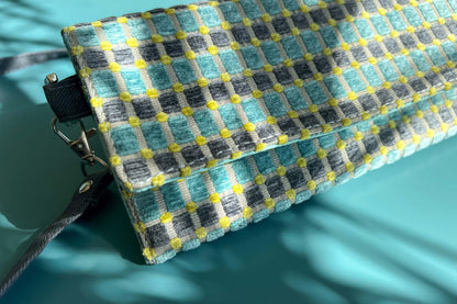 Detailansicht der kleinen Umhängetasche DANA aus upcycled Polsterstoff in den Farben blau, gelb und beige mit silbernen Verschlüssen. 