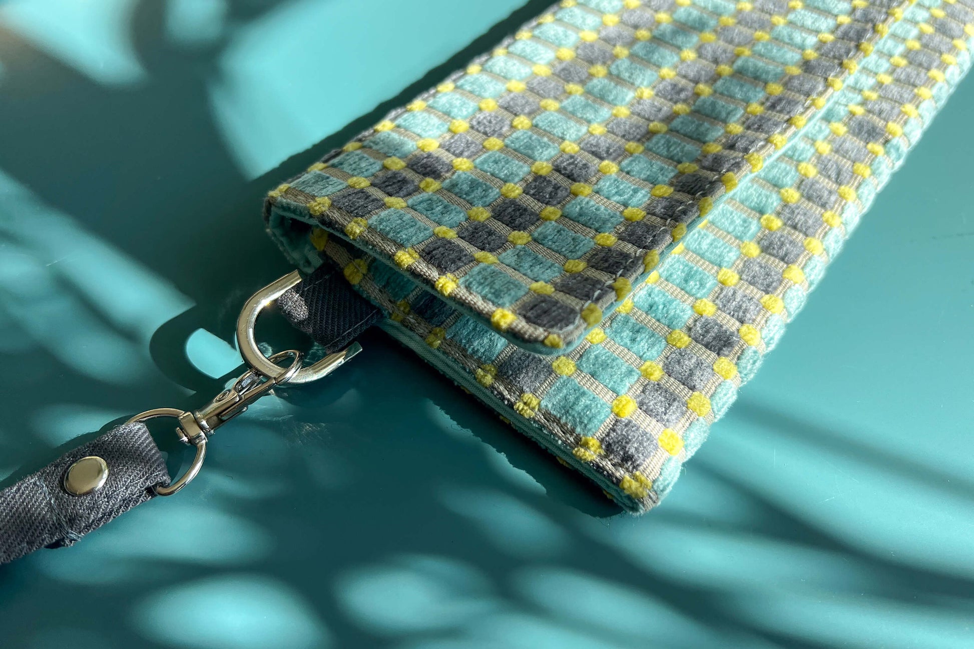 Detailansicht der kleinen Umhängetasche DANA aus upcycled Polsterstoff in den Farben blau, gelb und beige mit silbernen Verschlüssen. 