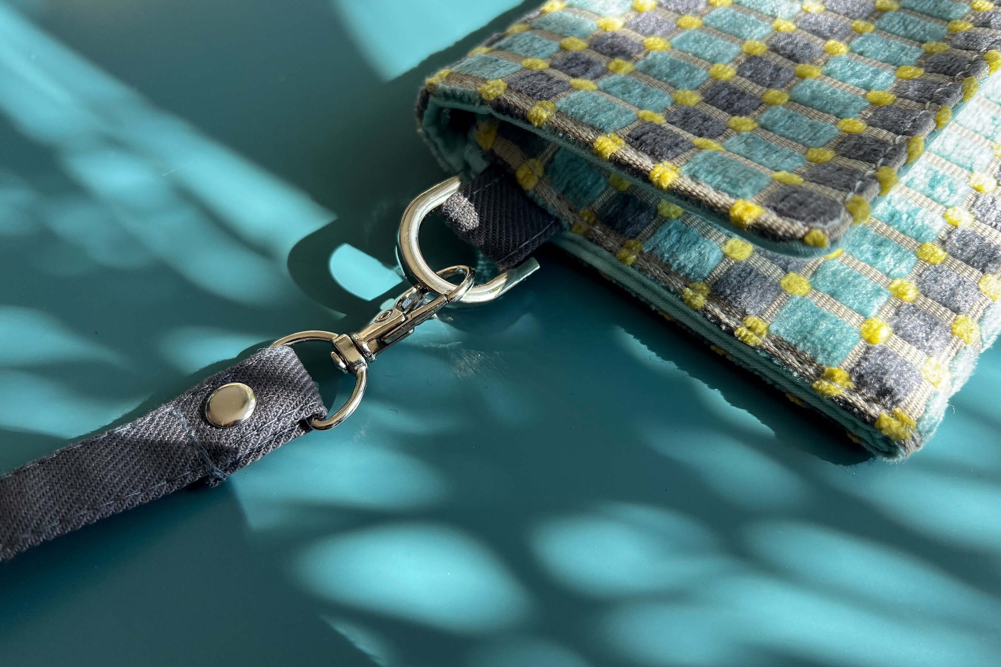 Detailansicht der kleinen Umhängetasche DANA aus upcycled Polsterstoff in den Farben blau, gelb und beige mit silbernen Verschlüssen. 