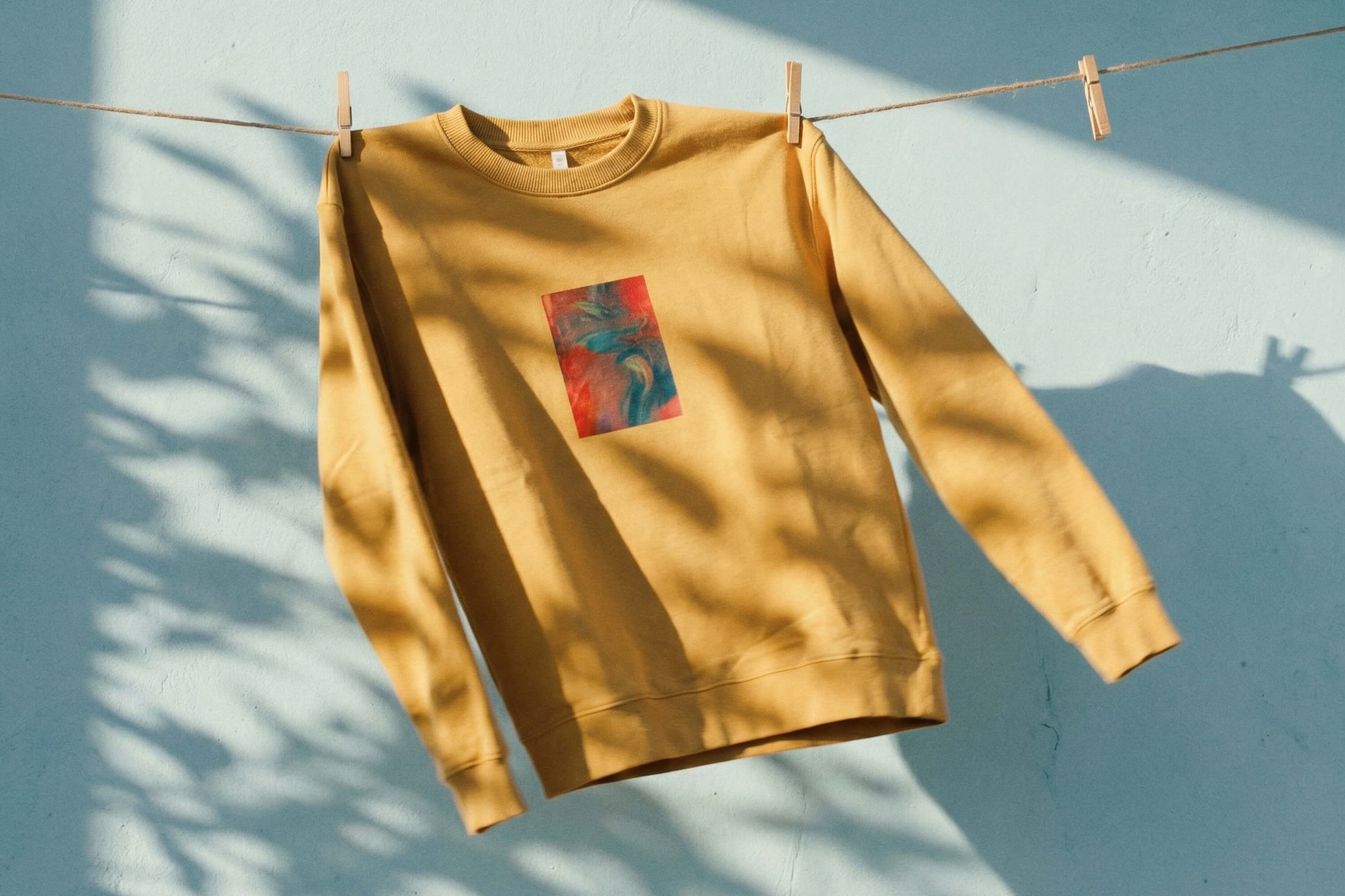 Frontansicht von senffarbenem senffarbenes Unisex Sweatshirt mit rot-blau-gelb verlaufendem Druck von einem großen Rechteck auf der Brust, bedruckt mit Siebdruck. 
