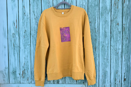 Frontansicht von senffarbenem senffarbenes Unisex Sweatshirt mit lila-gelb verlaufendem Druck von einem großen Rechteck auf der Brust, bedruckt mit Siebdruck. Siebdruck von Jeff EveryPieceAFriend.