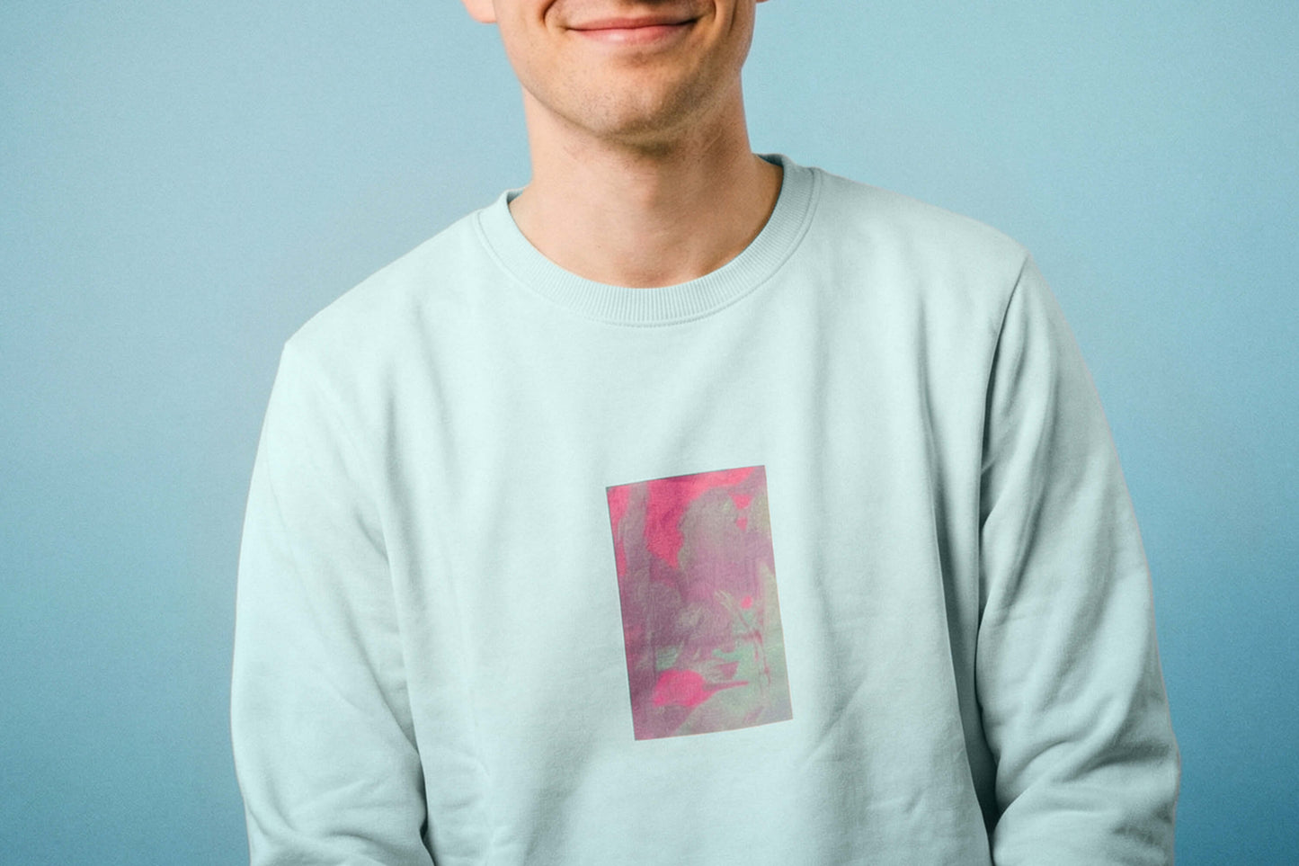 Detailanischt: ein junger Mann trägt ein hellblaues Unisex Sweatshirt mit lila-grün verlaufendem Druck von einem großen Rechteck auf der Brust, bedruckt mit Siebdruck. Siebdruck von Jeff EveryPieceAFriend.