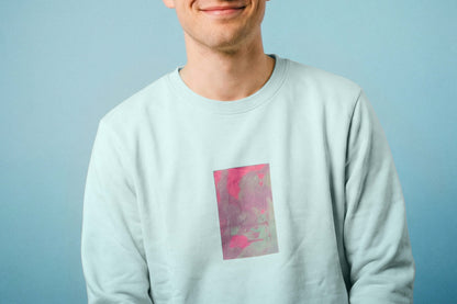 Detailanischt: ein junger Mann trägt ein hellblaues Unisex Sweatshirt mit lila-grün verlaufendem Druck von einem großen Rechteck auf der Brust, bedruckt mit Siebdruck. Siebdruck von Jeff EveryPieceAFriend.