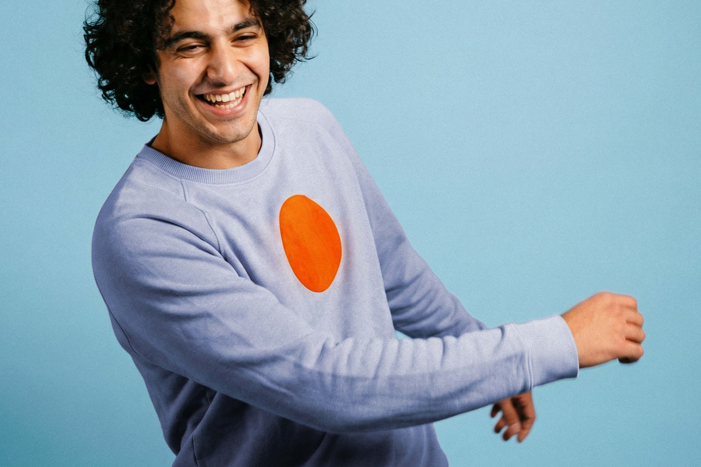 Detailanischt: ein junger Mann trägt ein Unisex Sweatshirt in der Farbe dusty purple mit orange-gelben, kreisrundem Druck auf der Brust, bedruckt mit Siebdruckfarben auf Wasserbasis. Siebdruck von Jeff EveryPieceAFriend.