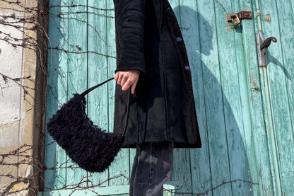 Eine Frau im schwarzen Mantel trägt die schwarze Schultertasche LUCIA aus einer pre-loved Weste im Vintage Look - jeff - EveryPieceAFriend