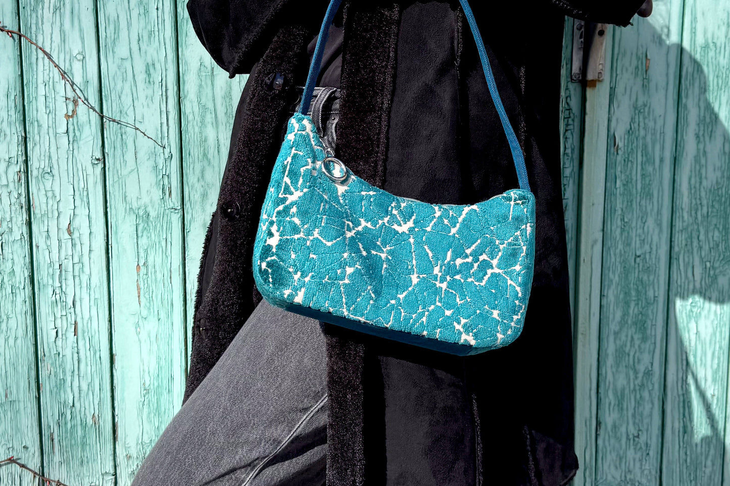 Eine Frau im schwarzen Mantel trägt die blaue Schultertasche LUCIA aus Polsterstoff im Vintage Look - jeff - EveryPieceAFriend