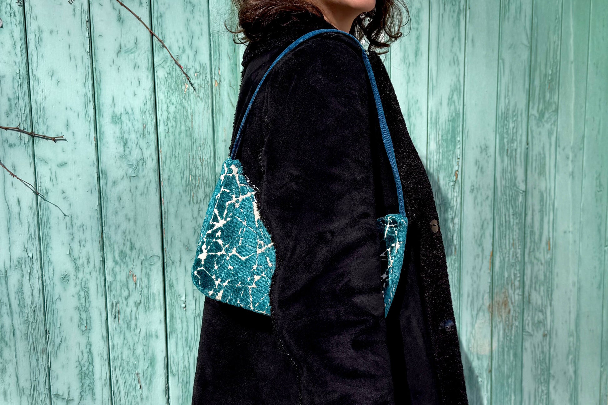 Eine Frau im schwarzen Mantel trägt die blaue Schultertasche LUCIA aus Polsterstoff im Vintage Look - jeff - EveryPieceAFriend