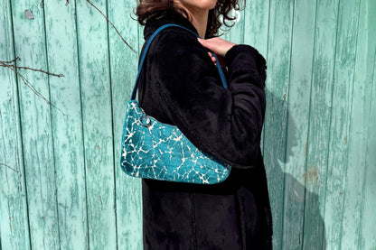 Eine Frau im schwarzen Mantel trägt die blaue Schultertasche LUCIA aus Polsterstoff im Vintage Look - jeff - EveryPieceAFriend. 
