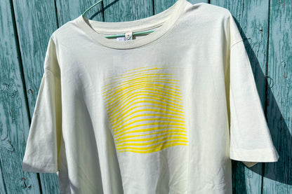 Detailansicht von einem hellgelben T-Shirt in Größe XL vor einem blauen Hintergrund. Das T-Shirt hat einen welligen Druck in gelb auf der Brust. Handbedruckt von Jeff - EveryPieceAFriend