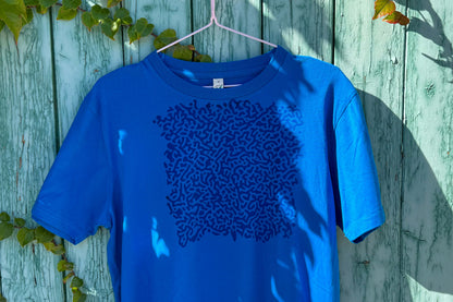 Detailansicht von einem blauen T-Shirt vor einem blauen Hintergrund. Das T-Shirt hat einen welligen Druck auf der Brust.